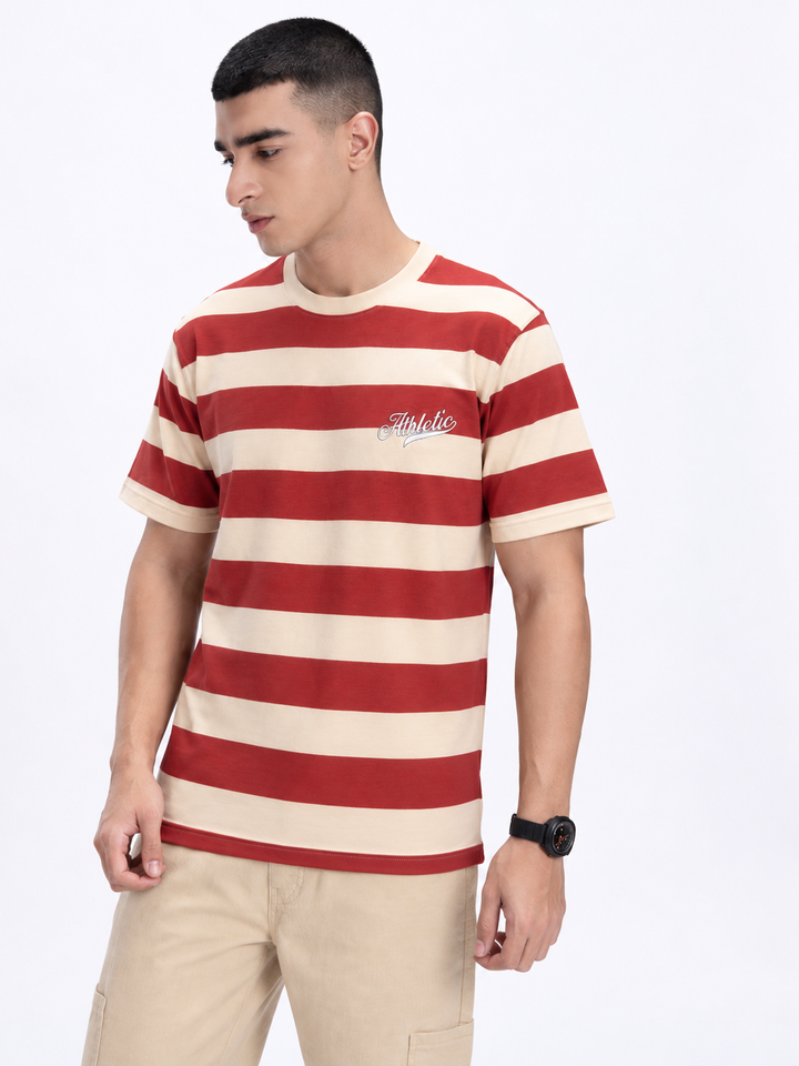 A man wearing a red and cream striped short-sleeve t-shirt with a small white script logo on the left chest, paired with beige cargo pants, against a plain white background.