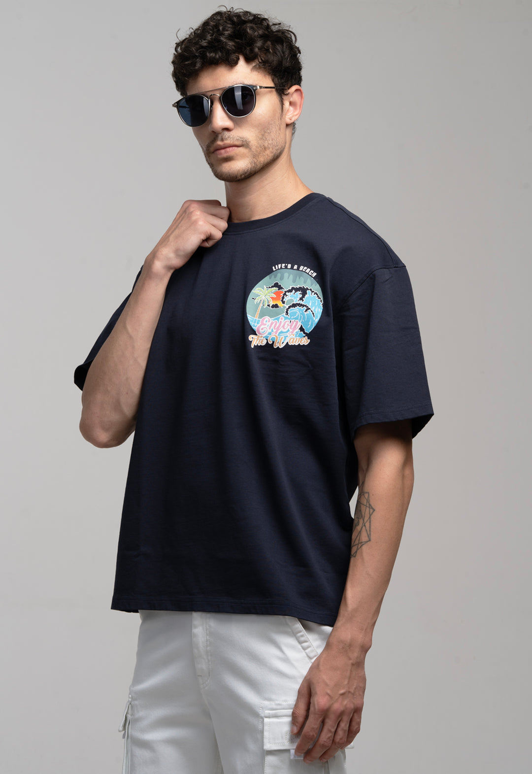 Man wearing a navy blue t-shirt with a graphic design on a plain background