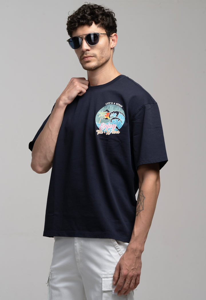 Man wearing a navy blue t-shirt with a graphic design on a plain background