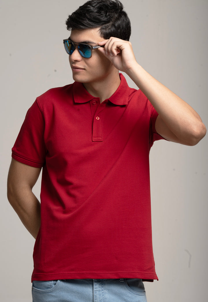 Man wearing a red polo shirt and sunglasses against a plain background