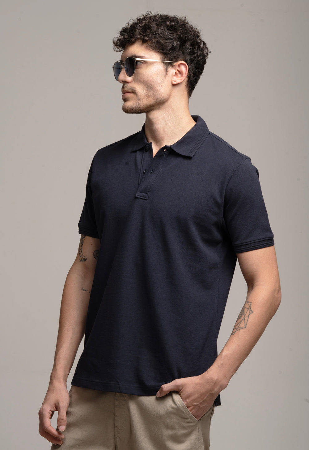 Man wearing a navy blue polo shirt against a gray background
