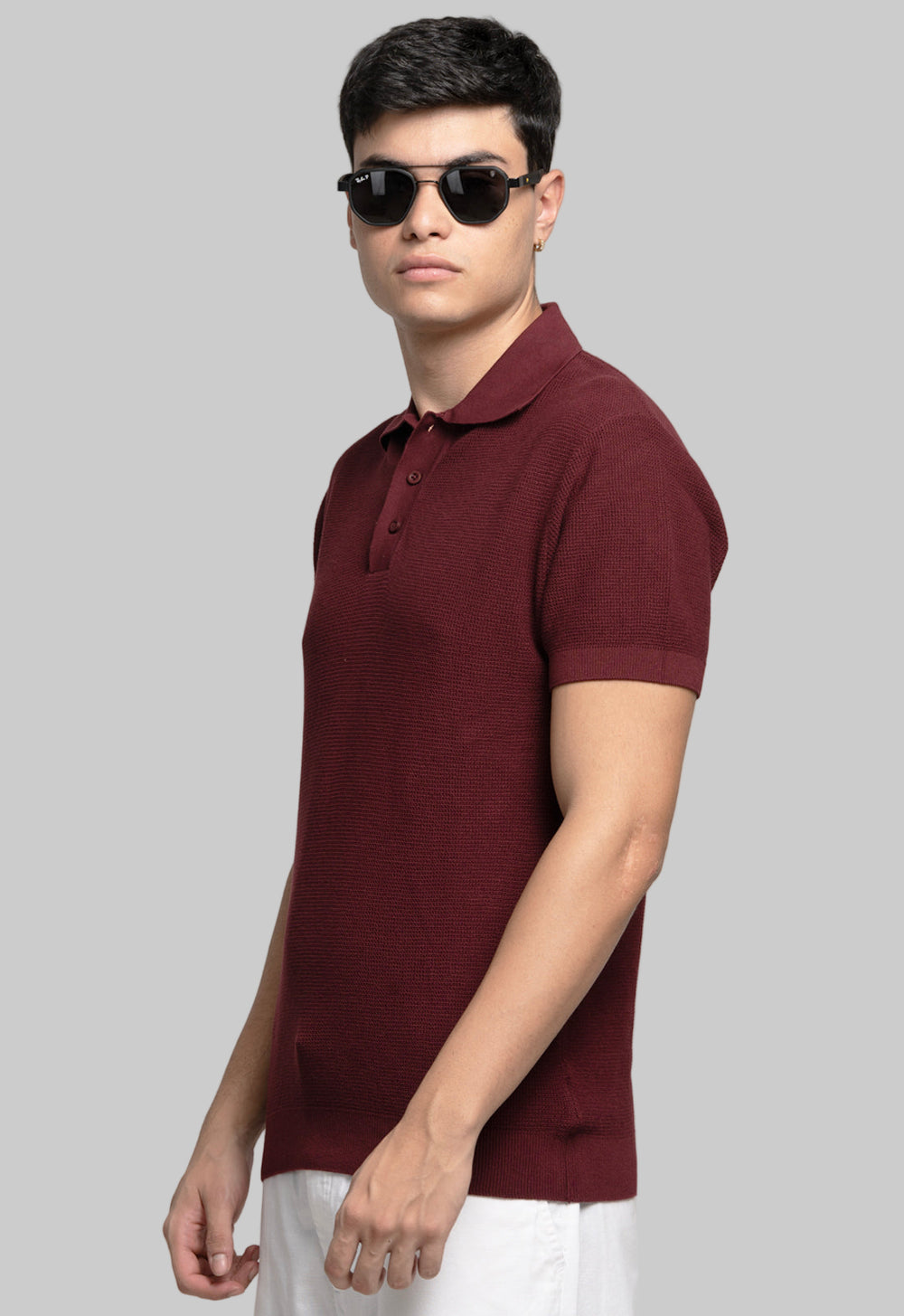 Man wearing a maroon polo shirt and sunglasses on a plain background