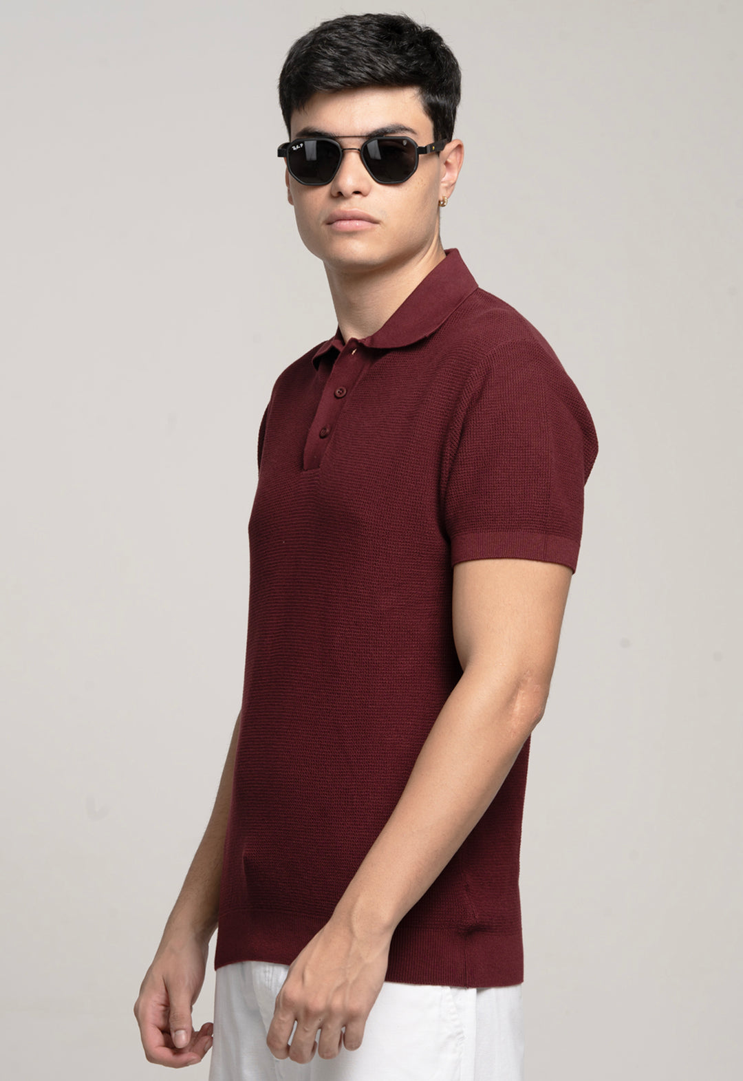 Man wearing a maroon polo shirt and sunglasses on a plain background