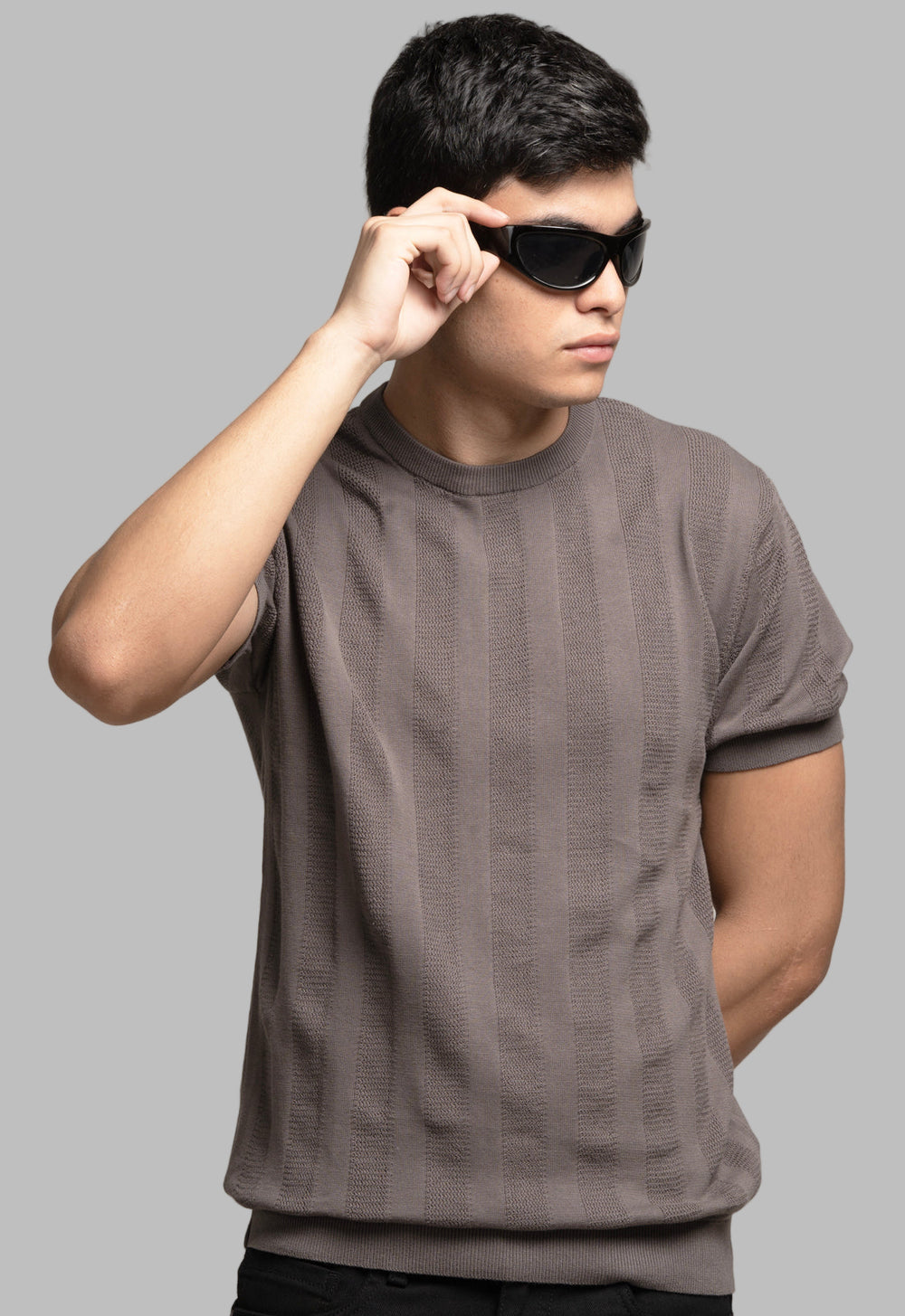 Man wearing a brown t-shirt and sunglasses against a plain background