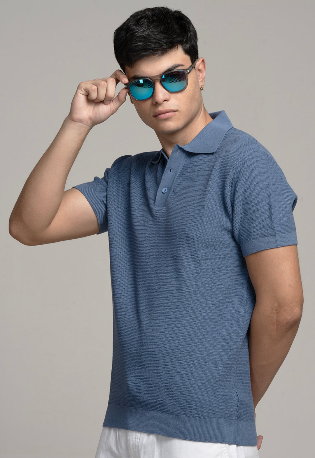 Man wearing a blue polo shirt and sunglasses against a gray background