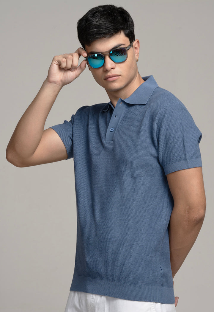 Man wearing a blue polo shirt and sunglasses against a gray background