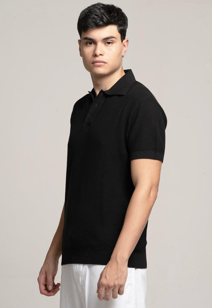 Man wearing a black polo shirt against a plain background