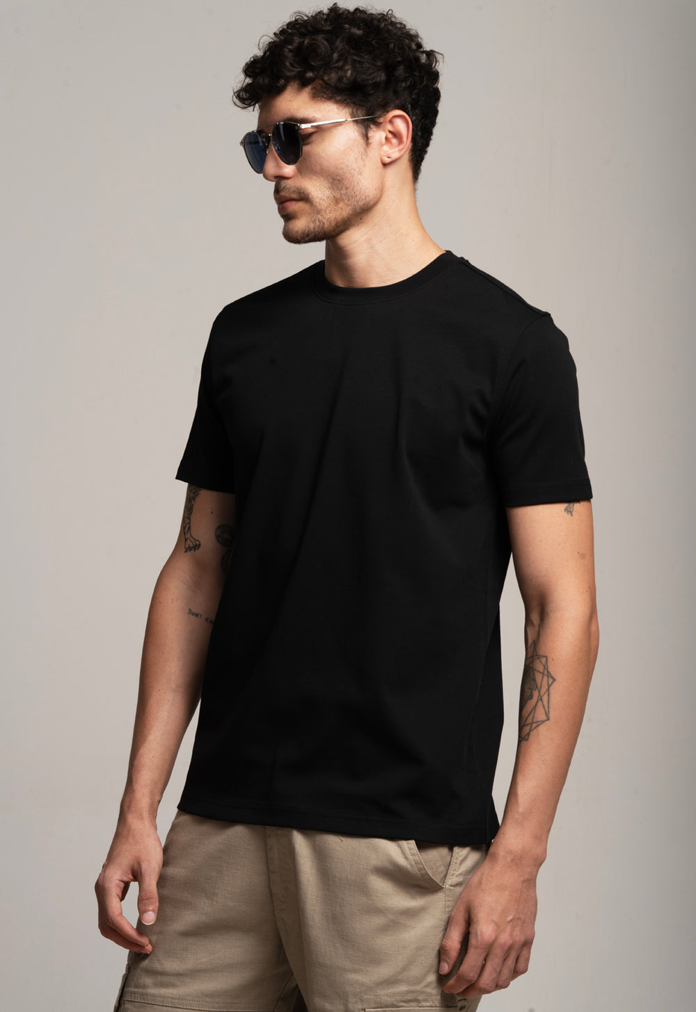 Man wearing a black t-shirt and sunglasses against a plain background