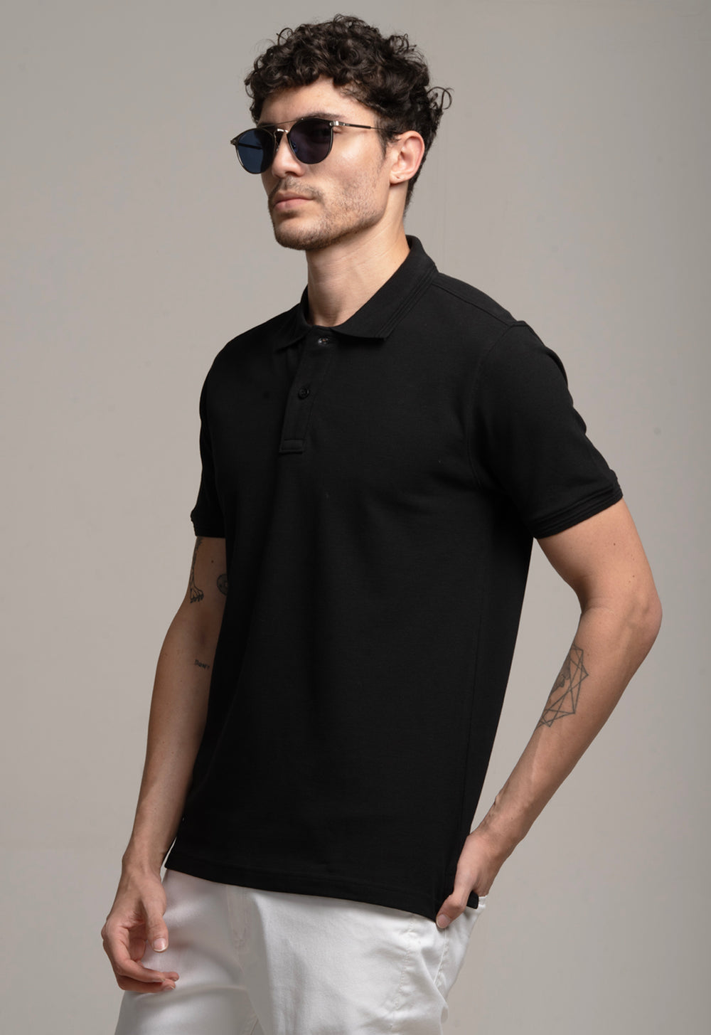 Man wearing a black polo shirt and sunglasses against a gray background