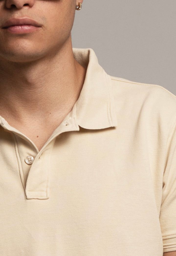 Close-up of a person wearing a beige polo shirt against a gray background